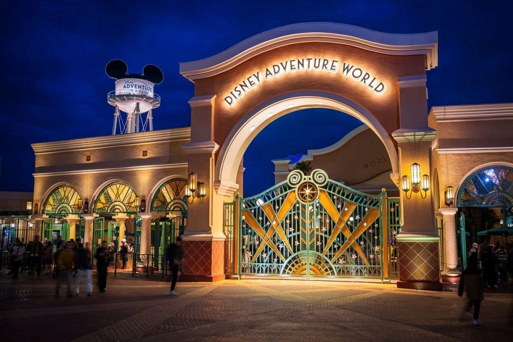 Entrada de Disney Adventure World en Disneyland® Paris, con su portal iluminado de noche.