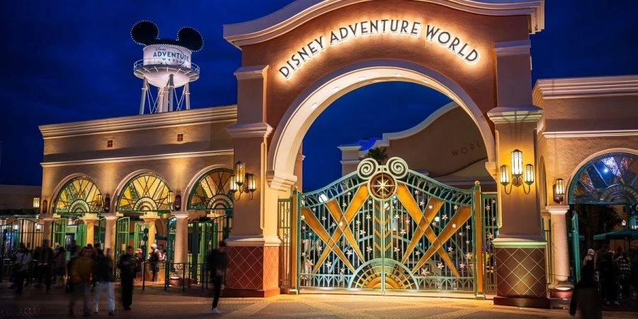 Entrada de Disney Adventure World en Disneyland® Paris, con su portal iluminado de noche.